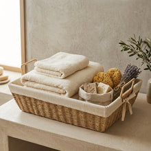 Naturel opbergmand gevuld met handdoeken, sponzen, zeep en decoratieve takken