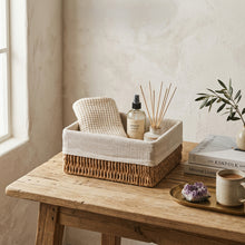 Jute opbergmand op houten tafel, gevuld met doek, sprayflacon en geurstokjes