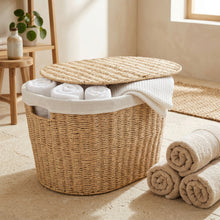 Naturel wasmand gevuld met opgerolde handdoeken en deksel half geopend
