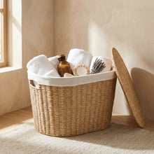 Open naturel wasmand met handdoeken en badkamerartikelen, deksel ernaast