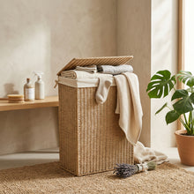 Naturel jute wasmand met geopend deksel, gevuld met lichtgekleurd wasgoed