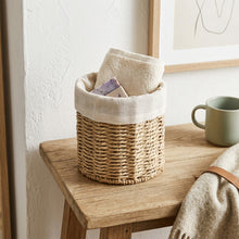 Naturel opbergmand met linnen rand en textiel op een houten tafel