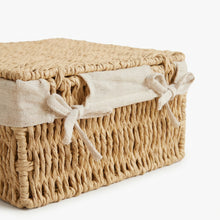 Detail van een naturel opbergmand met deksel en naar buiten gevouwen voering met strikken