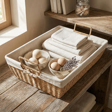 Boho opbergmand op een houten tafel, gevuld met gevouwen textiel en decoratieve accessoires