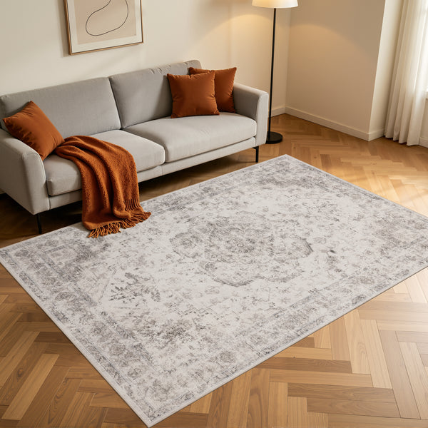 Rechthoekig beige Inka vloerkleed op een houten vloer voor een grijze bank
