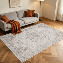 Rechthoekig beige Inka vloerkleed op een houten vloer voor een grijze bank